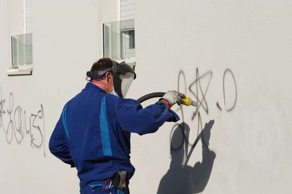 Mitarbeiter entfernt Graffiti von einer weißen Fassade